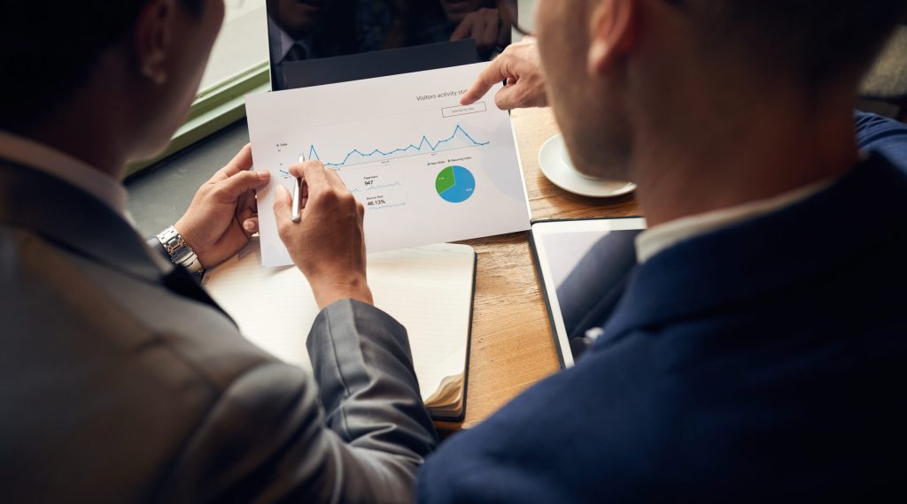 Business people analyzing visitors activity statistics, view over the shoulder