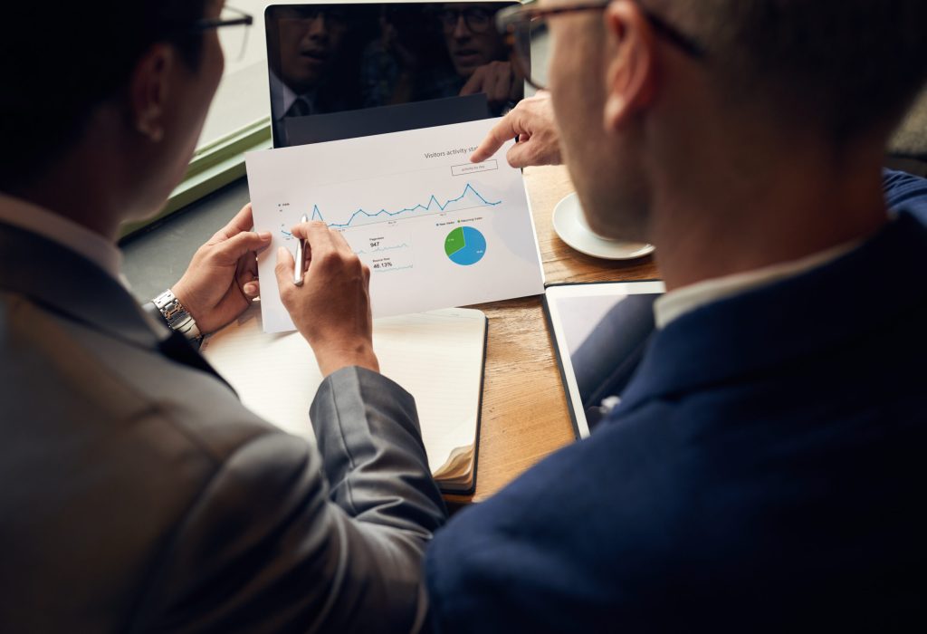 Business people analyzing visitors activity statistics, view over the shoulder