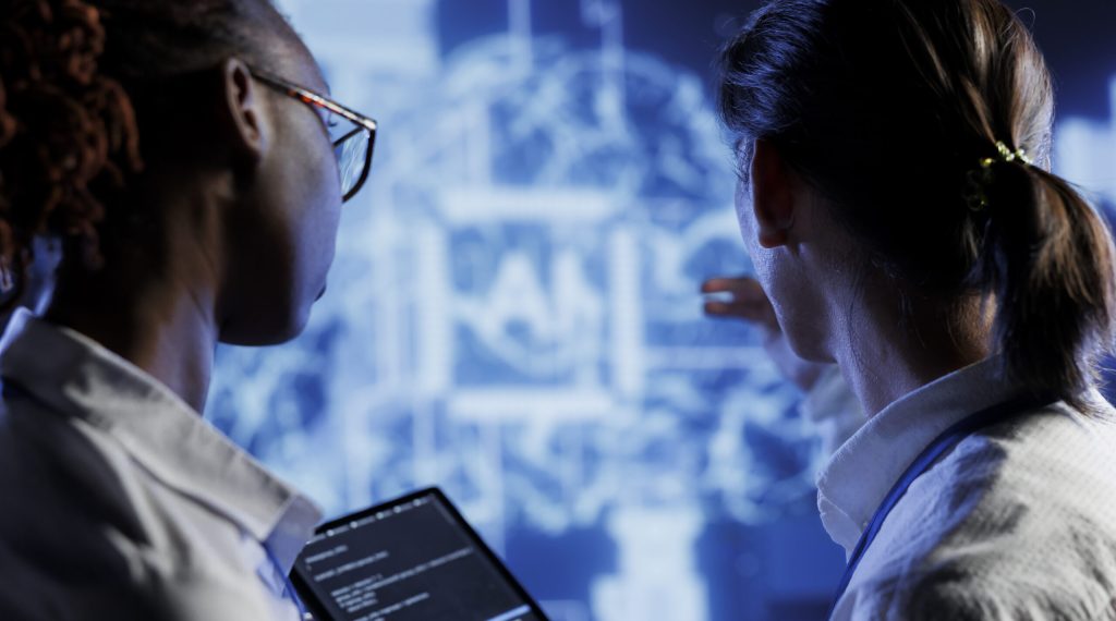 IT consultants brainstorm ways to use AI cognitive computing to extract usable information from complex data. High tech facility workers implement artificial intelligence to process inference datasets