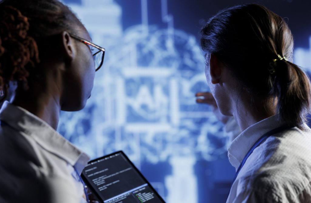IT consultants brainstorm ways to use AI cognitive computing to extract usable information from complex data. High tech facility workers implement artificial intelligence to process inference datasets