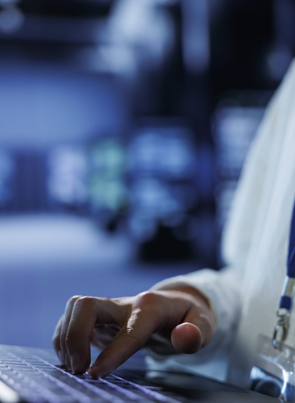 Knowledgeable admin in data center uses laptop to prevent system overload during peak traffic periods. Adept expert in server hub ensuring enough network bandwidth for smooth operations, close up