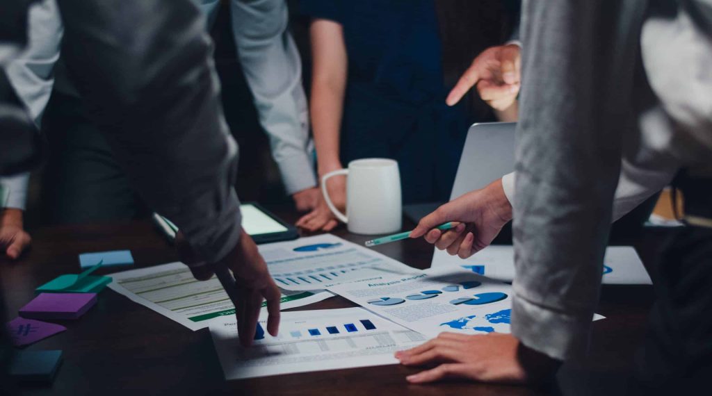 Millennial Asia businessmen and businesswomen meeting brainstorming ideas about new paperwork project colleagues working together planning success strategy enjoy teamwork in small modern night office.