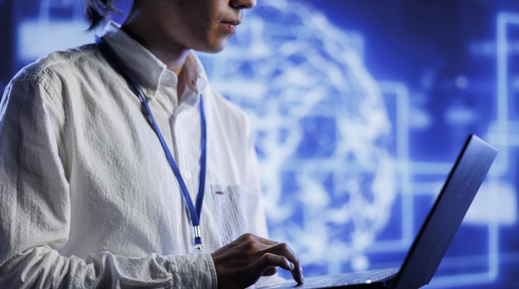 System administrator using laptop to maintenance artificial intelligence neural networks simulating human thought processes in computerized model. Adept professional doing checkup on AI systems